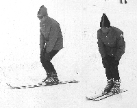  Marjan Svetličič in Miro Dvoršak z rokami na kolenih nazorno učencem kažeta potiskanje kolen levo in desno po GLM, da učenec vijuga blizu vpadnice na bolj položnem smučišču (1973).