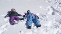  Otroka sta vtisnila vsak svojo podobo v sneg.  
