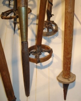  Različne konice smučarskih palic, nekatere opremljene z lesenimi krpljicami iz upognjene letvice ter leseno polno krpljico. Lovci so uporabljali dvonamenski kolec z ostro kovinsko konico za odrivanje med drsenjem na smučeh in tudi kot kopje, ko so ubijali divjačino (Smučarski muzej Umeå, Švedska).