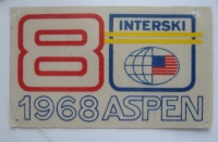 Tekstilna nalepka INTERSKI kongresa, Aspen, ZDA, 1968. Jože Uršič je bil edini Slovenec, ki se ga je udeležil. Nastop slovenske vrste je preprečila Smučarska zveza Jugoslavije (sedež v Beogradu), čeprav so demonstratorji sami zbrali denar za pokrivanje stroškov kongresa.